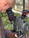 Person holding a Canon video camera outdoors with greenery in the background